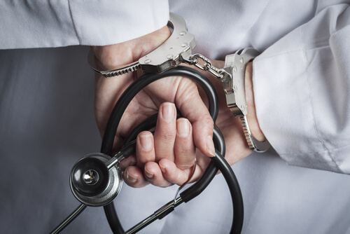 Female,Doctor,Or,Nurse,In,Handcuffs,And,Lab,Coat,Holding